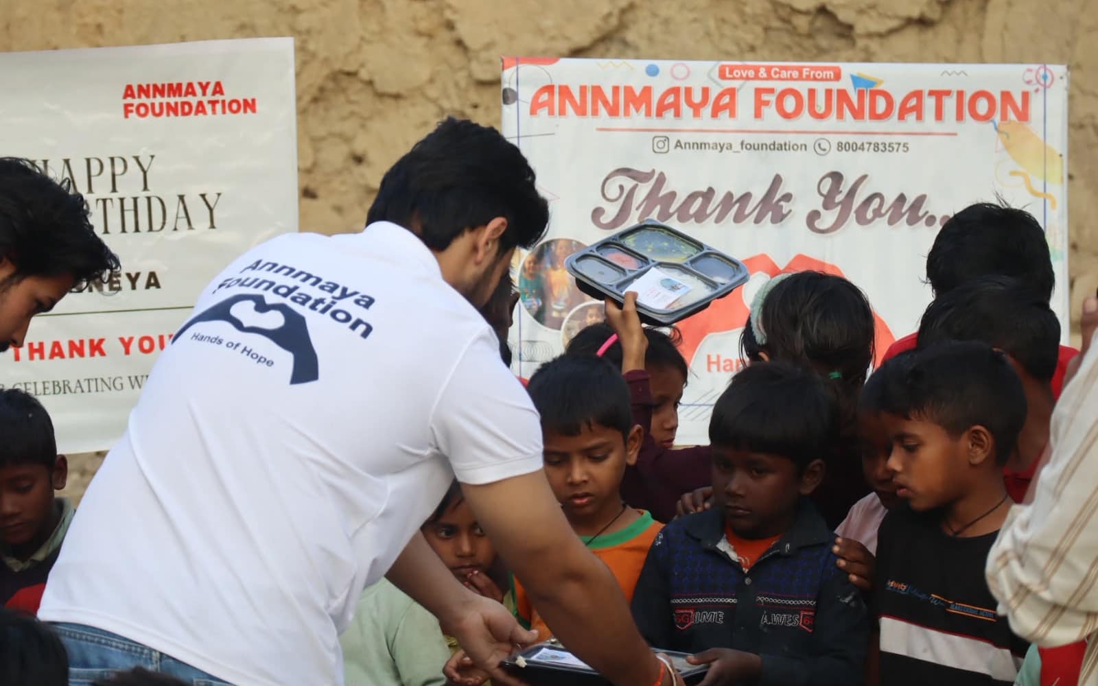 Annmaya Foundation volunteers and children beside the foundation’s thank-you banner